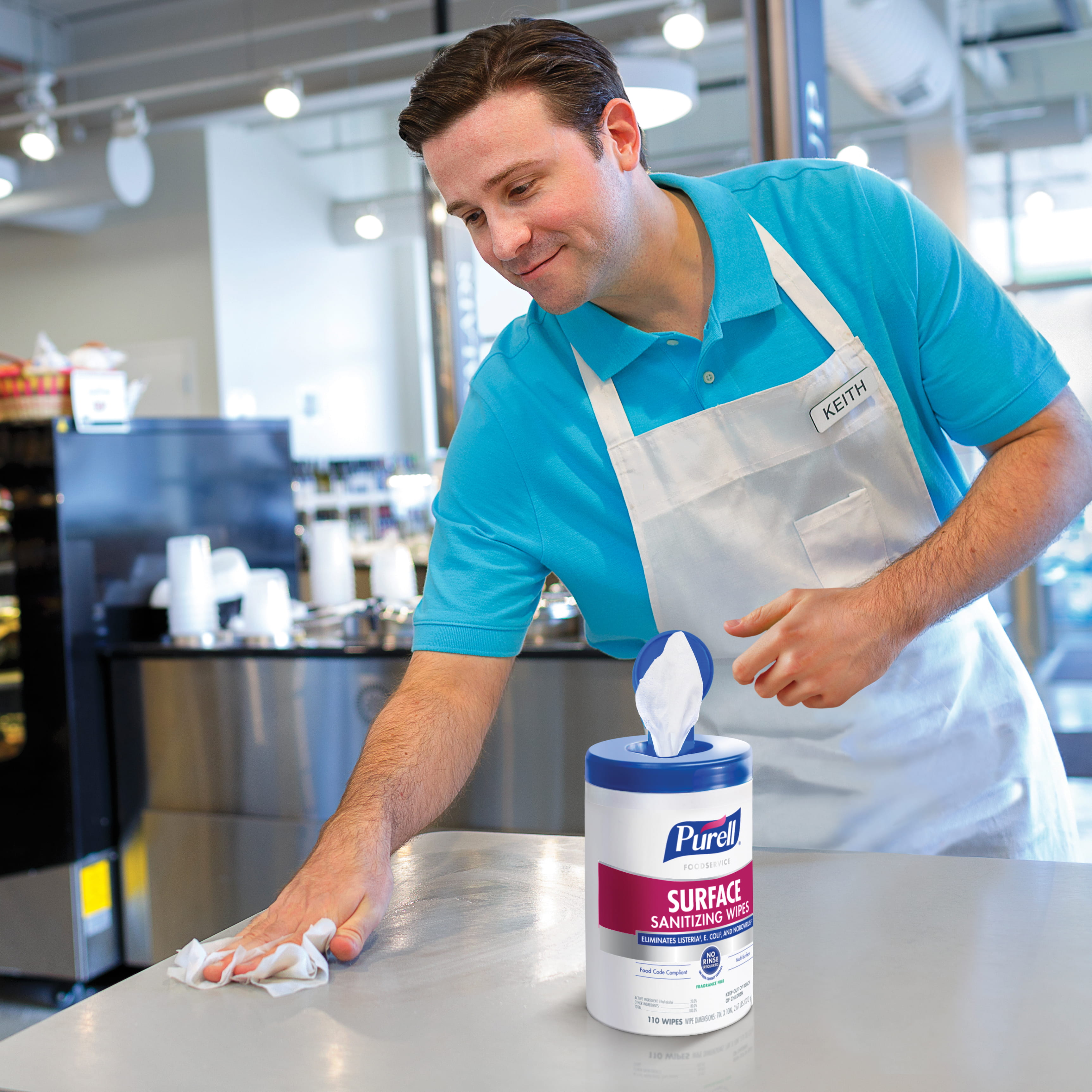 Convenience store employee cleans surface with PURELL disinfectant wipes