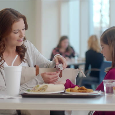 Mother pumping hand sanitizer into daughter's hand at dining table