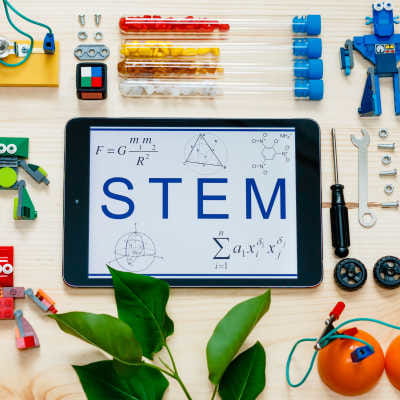 Graphic of a tablet with the word "STEM" on it and STEM tools