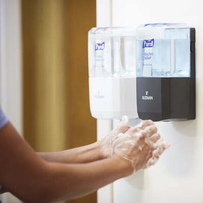 Washing hands with PURELL Brand HEALTHY SOAP with PURELL Hand Sanitizer dispenser next to soap