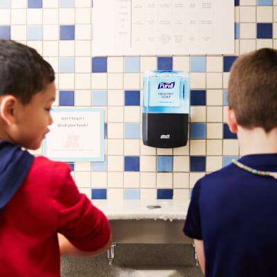 Two boys washing their hands at a school bathroom sink 