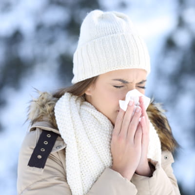 Woman blowing her nose outside in the snow