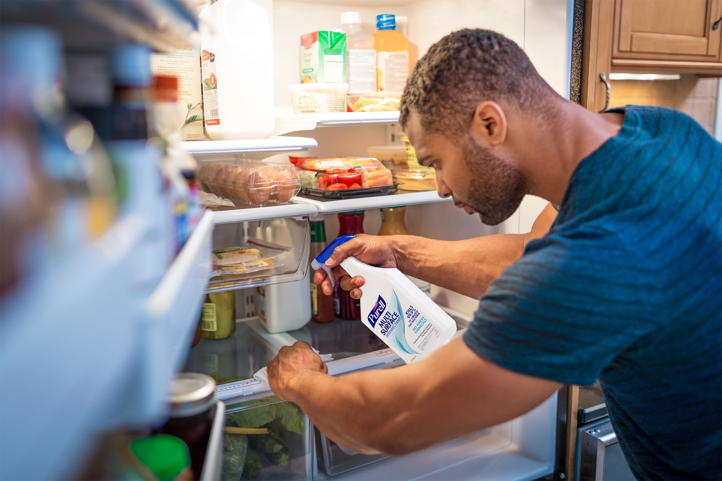 A man cleans his fridge with PURELL Surface Disinfectant