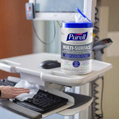 A nurse wiping down a computer keyboard with PURELL Surface wipes