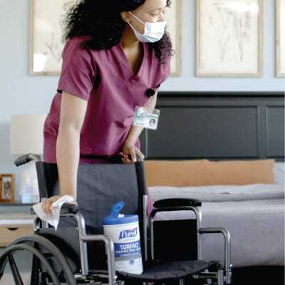 A nurse in a hospital using PURELL surface wipes to wipe down a wheelchair