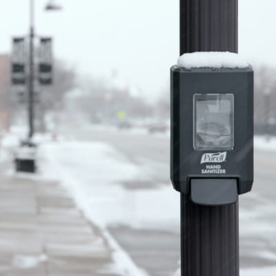 PURELL® CS4 All-Weather Dispensing System mounted on pole on city street, covered in snow